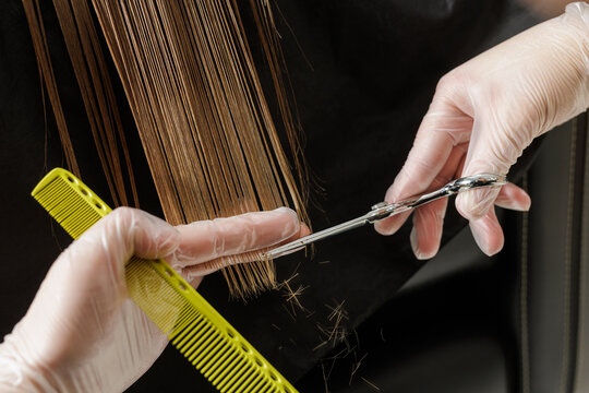 Precision wet haircut with scissors and comb as cut ends fall in salon