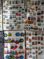 An vibrant assortment of handcrafted earrings displayed for sale, showcasing a rich variety of materials like wood, metal, and colorful threads. Perfect for fashion, accessory, or market-themed