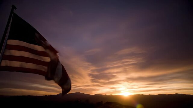Flag waving at sunset. Mountain silhouette meets sky on horizon. Warm dusk light paints clouds and landscape. Gentle breeze ripples fabric. Serene nature mood for travel outdoor projects and business.