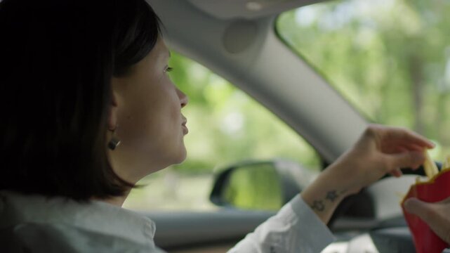 Woman Eating French Fries While Driving. Distracted Driving Scene