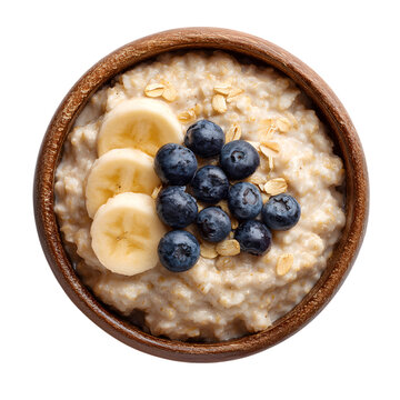 Overhead view of oatmeal with banana slices and blueberries in a wooden bowl on transparent background