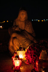 Night scene of a cemetery illuminated by hundreds of candles during All Saints Day. Warm glowing lights, bokeh and flowers creating a peaceful, spiritual atmosphere. Shot in Biały Kościół, Poland.