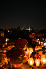Night scene of a cemetery illuminated by hundreds of candles during All Saints Day. Warm glowing lights, bokeh and flowers creating a peaceful, spiritual atmosphere. Shot in Biały Kościół, Poland.