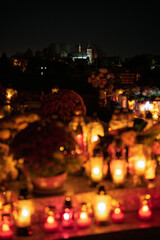 Night scene of a cemetery illuminated by hundreds of candles during All Saints Day. Warm glowing lights, bokeh and flowers creating a peaceful, spiritual atmosphere. Shot in Biały Kościół, Poland.