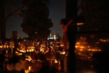 Night scene of a cemetery illuminated by hundreds of candles during All Saints Day. Warm glowing lights, bokeh and flowers creating a peaceful, spiritual atmosphere. Shot in Biały Kościół, Poland.