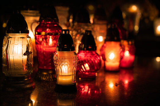 Night scene of a cemetery illuminated by hundreds of candles during All Saints Day. Warm glowing lights, bokeh and flowers creating a peaceful, spiritual atmosphere. Shot in Biały Kościół, Poland.