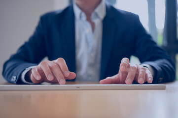 Close-up of businessman in formal suit typing on computer keyboard at office desk, representing professional work, corporate communication, productivity, and modern digital business concept