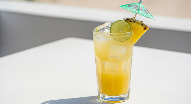 Refreshing pineapple cocktail with lime garnish and mini umbrella for summer vibes, perfect for vacation advertisements and tropical themed events