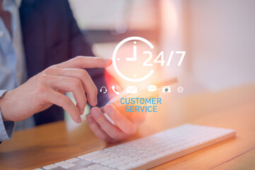 Close-up of businessman using smartphone and keyboard with 24/7 customer service icons, symbolizing online communication, technical support, help desk, and professional client assistance.