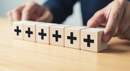 Positive Alignment: A close-up view captures a hand carefully arranging wooden blocks, each bearing a prominent plus sign, to form a visually striking sequence on a wooden surface.