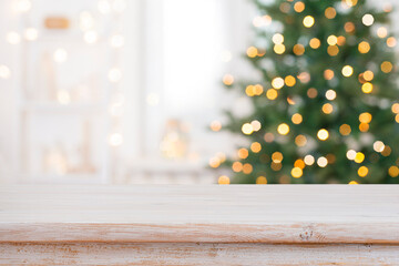 Bleached wood table top for your product presentation on deeply blurred Christmas fir tree lights interior background