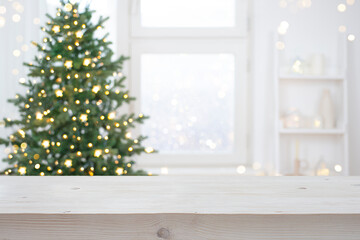 Light color wood table top for your product presentation on blurred Christmas tree decoration interior background