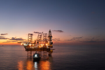 Obraz premium Aerial view of offshore jack up rig and offshore platform during sunset for oil and gas exploration and production.