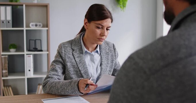 Interview recruitment in office manager meets candidate. HR manager checks documents, noting experience and fit, and discusses eligibility with applicant job seeker. Hiring and employee recruit.