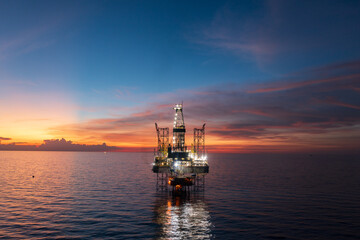 Aerial view of offshore jack up rig and offshore platform during sunset for oil and gas exploration and production.