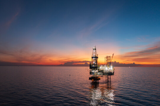 Aerial view of offshore jack up rig and offshore platform during sunset for oil and gas exploration and production.