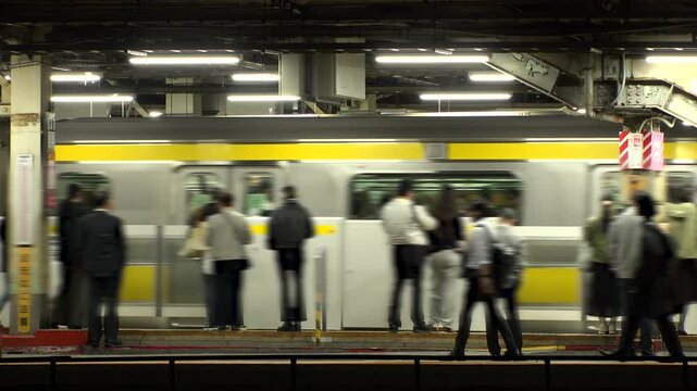 TOKYO, JAPAN - NOV 2025 : View of train station in Tokyo. Crowd of people at the platform in busy night rush hour. Japanese urban city life, transportation, traffic and commute concept video.