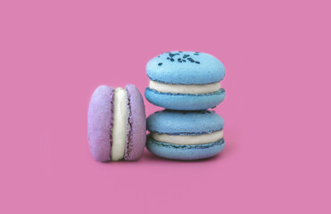 Three multicolored macarons on a pink background