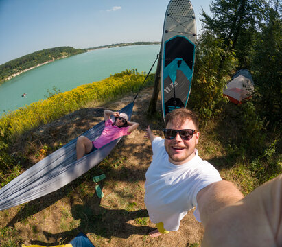 Couple Enjoying Lakeside Camping with Paddleboard taking selfie