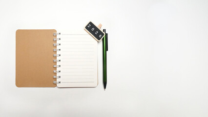 Top view of a blank notebook and pen with '2026' text, symbolizing New Year's goals, resolution planning, future strategy, and business management. Ideal for productivity and success concepts.