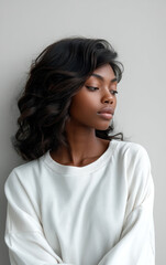 Obraz premium Elegant black woman with wavy hair wearing white sweater, looking away, calm expression, soft natural light, studio portrait