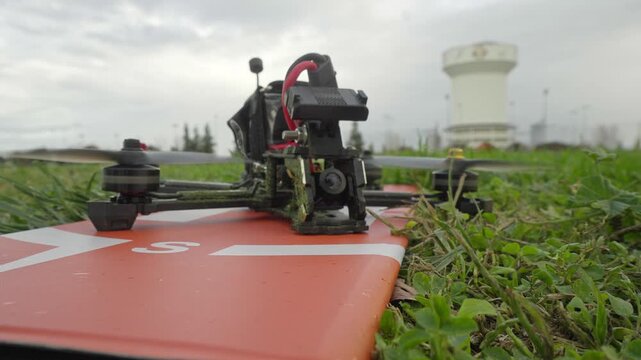 A simple flick of the transmitter switches the FPV drone into arm mode, the camera capturing its quiet readiness on the field.