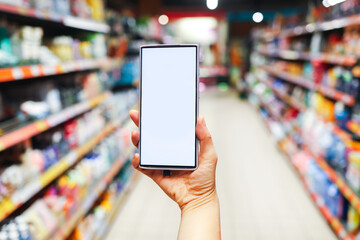 Woman holding a smartphone at a supermarket, online shopping concept.