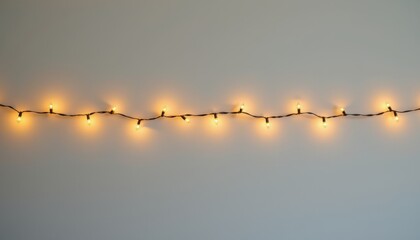 Warm white string lights illuminate a plain light gray wall with empty space above