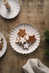 Gebackene Zimtsterne Kekse auf einem Teller und eine Kerze auf einem rustikalen Holz Tisch. Draufsicht, Dessert, Weihnachten.