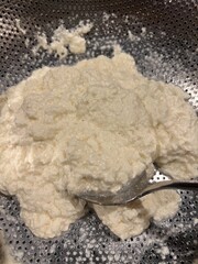  Close-up of a spoon resting in thick cheese curds during the draining process