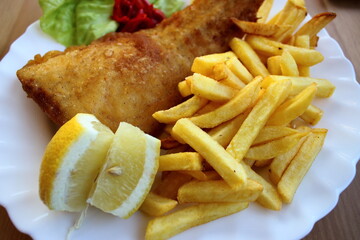 Fried fish and chips with lemon on white plate