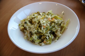 Cabbage salad with peas and carrots in white bowl