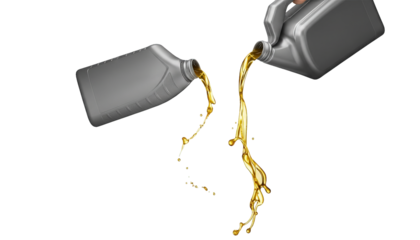 Motor oil is poured from two containers, creating a dynamic stream against transparency.