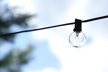 Obraz premium Outdoor string light with blue sky background, cozy summer atmosphere