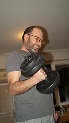 Man smiling and lifting weights at home