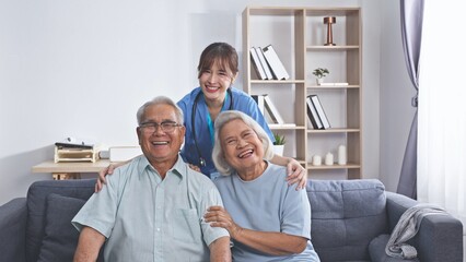 Asian female doctor and elderly couple smiling happily after home health check up, showing...