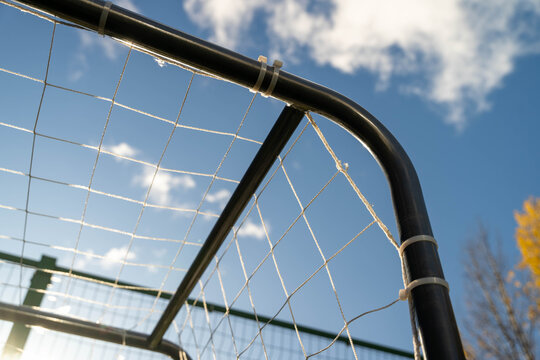 Soccer goal frame with netting against a bright blue sky, showcasing the structure and design of sports equipment, ideal for athletic and outdoor themes