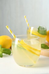 Fresh lemonade in glasses, lemon and mint on white table, closeup