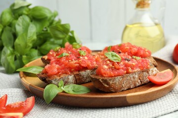 Tasty bruschettas with tomatoes and basil on table, closeup
