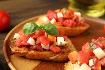 Tasty bruschettas with tomatoes, mozzarella cheese and basil served on wooden table, closeup