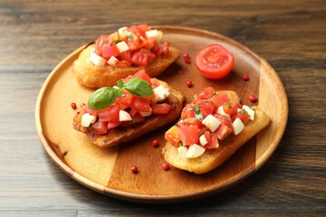 Tasty bruschettas with tomatoes, mozzarella cheese and basil served on wooden table, closeup