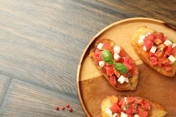 Tasty bruschettas with tomatoes, mozzarella cheese and basil served on wooden table, top view....