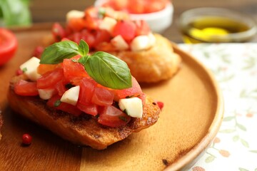 Tasty bruschettas with tomatoes, mozzarella cheese and basil served on table, closeup