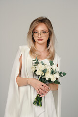 Portrait of a girl in a white suit holding flowers. Female portrait.