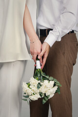 A man's and woman's hands holding a white bouquet of flowers. Wedding concept.