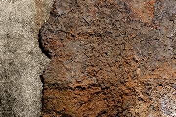 Real textured background of a dry, cracked red clay wall with a broken concrete surface, peeling off with border. For use concept of erosion, damage, and decay for abstract or grunge design themes