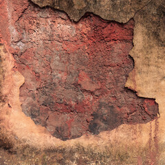 Real textured background of a dry, cracked red clay wall with a broken concrete surface, peeling off with border. For use concept of erosion, damage, and decay for abstract or grunge design themes