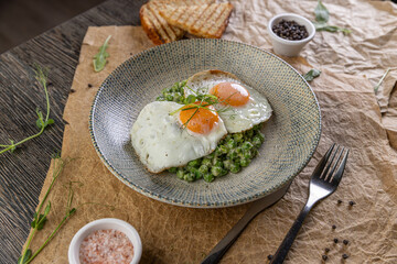 Plate of fried eggs on green peas puree
