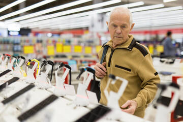 elderly man examines smart watch in showroom of electronics store