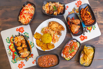 Vari&eacute;t&eacute; de plats antillais et cr&eacute;oles (accras de morue, colombo de poulet, fricass&eacute;e de chatrou, court-bouillon de poisson, griot de porc, pikliz, riz Djon Djon, bananes pes&eacute;es) sur une table en bois 